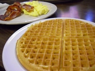 A golden Belgian waffle served with scrambled eggs and bacon at Lincoln's Waffle Shop